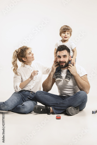 The happy family with kid sitting together and smiling at camera isolated on white studio background