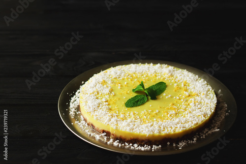 Healthy dessert - raw vegan lemon and coconut cake on black wooden background - gluten free, lactose free