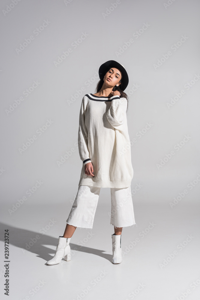 attractive african american girl in stylish white clothes and hat looking at camera on white attractive african american girl in stylish white clothes and hat looking at camera on white