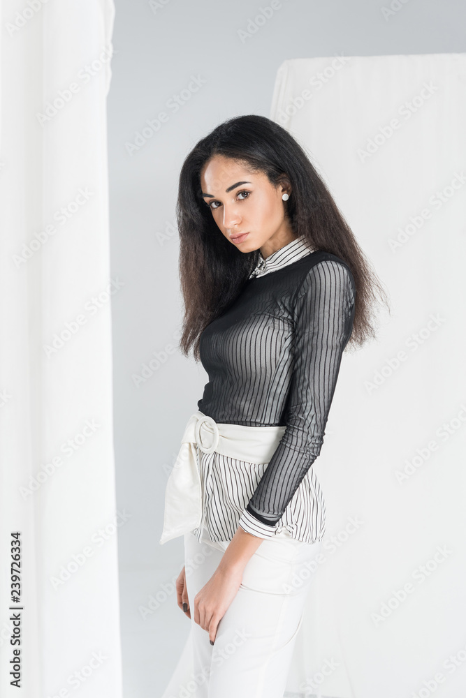 portrait of beautiful african american girl in stylish clothes standing near tulle on white portrait of beautiful african american girl in stylish clothes standing near tulle on white