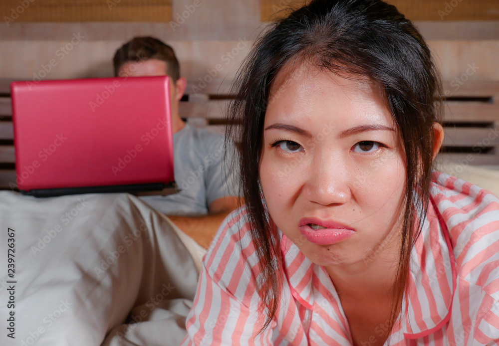 frustrated Korean woman in bed ignored by workaholic husband or internet social media addict boyfriend networking with laptop in bed ignoring the woman in Asian couple problem frustrated Korean woman in bed ignored by workaholic husband or internet social media addict boyfriend networking with laptop in bed ignoring the woman in Asian couple problem