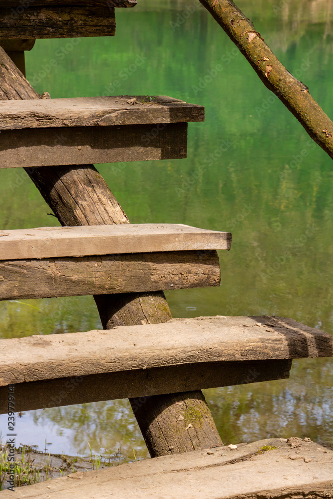 Steps of the elevated wooden walkway along Zlatna Panega River at Iskar-Panega Eco-path Geopark, partial view against the river water surface Steps of the elevated wooden walkway along Zlatna Panega River at Iskar-Panega Eco-path Geopark, partial view against the river water surface