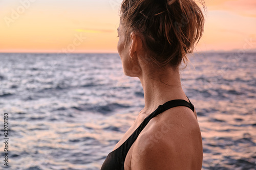 Woman in bra stretching near sea