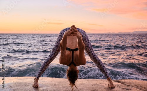 Flexible female bending forward near sea photo