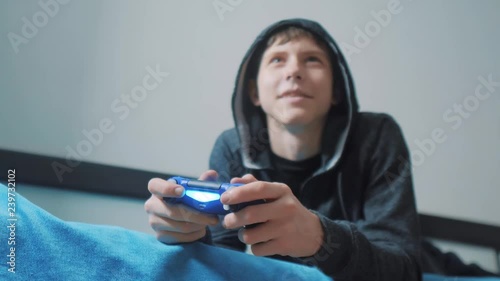 Wallpaper Mural young teen and joystick man cybersport hooded sweater absorbed In online video game. boy teenager in the hood playing video games on the console on the gamepad. Controller console gamepad. Gaming man Torontodigital.ca