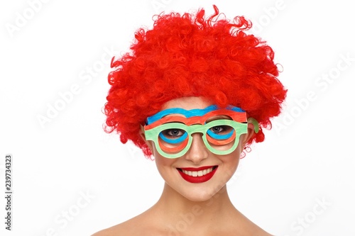 Portrait of a young woman in the image of a clown with a red wig on her head photo