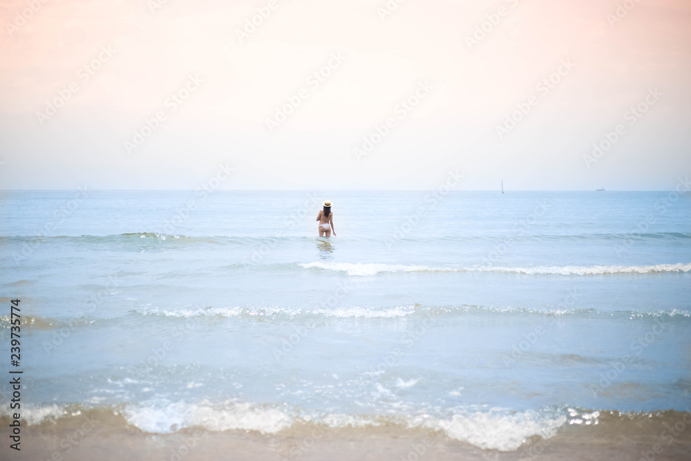 mujer bañándose en el mar con sombrero de paja