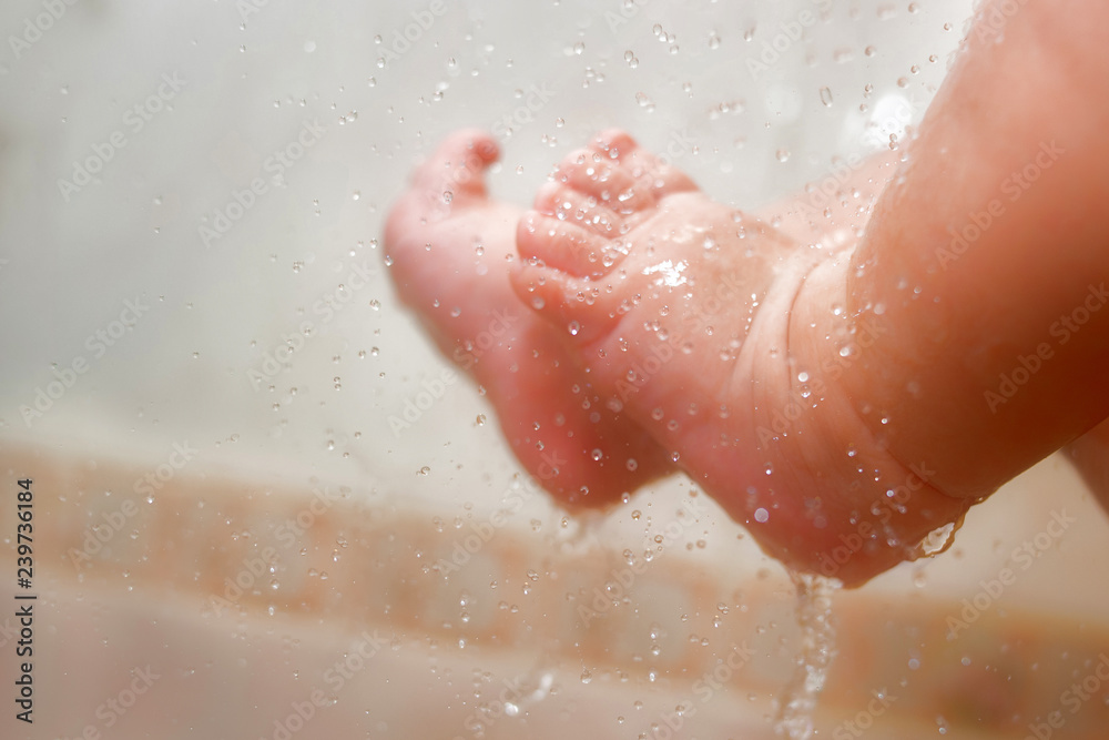 Baby's Feet Under The Shower With Lots Of Drops. Baby's Ankle In The Water. Parents Wash Their