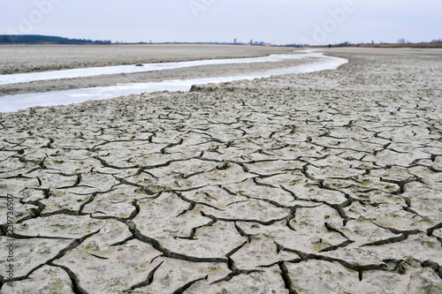 Cracks in the channel of the dried-up river covered with ice in the autumn. Background, texture, ecology photo