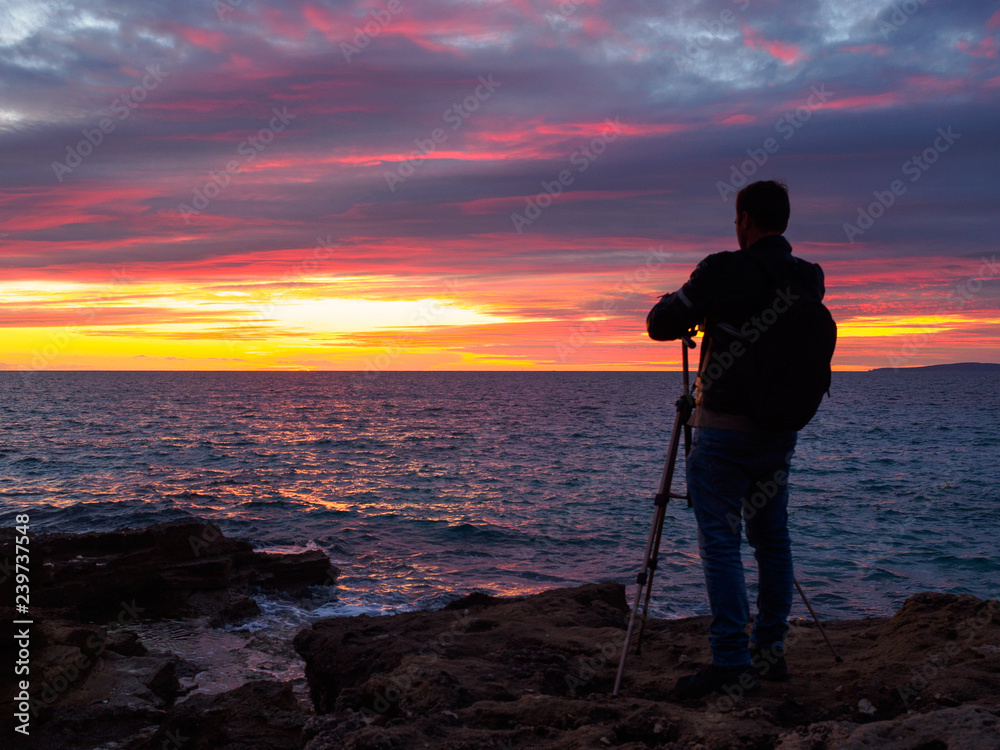 Silueta de un fotógrafo haciendo una fotografía de una puesta de sol en el mar en Mallorca