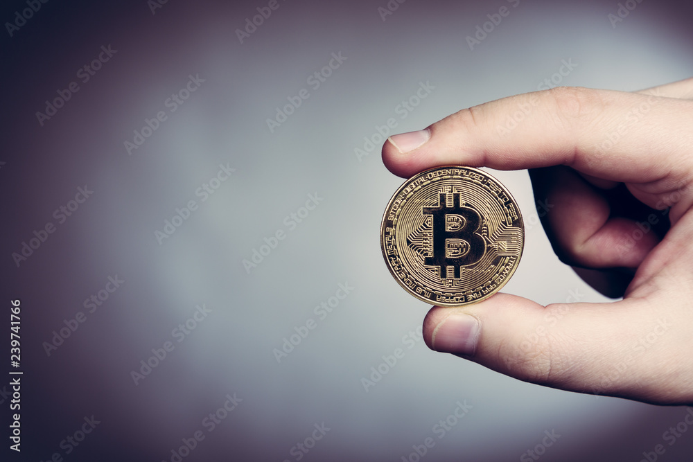 Bitcoin cryptocurrency gold coin in man's hand Bitcoin cryptocurrency gold coin in man's hand