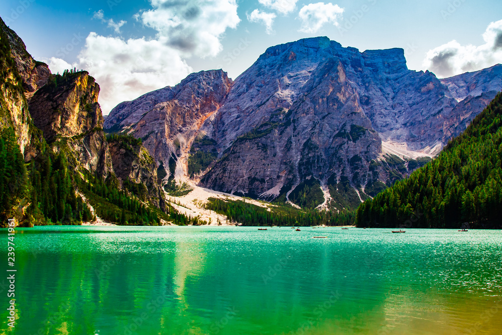 beautiful view of the Braies lake in Trentino Alto Adige, Italy, in the green water you can see the rocky mountain reflected, and the boats in exploration