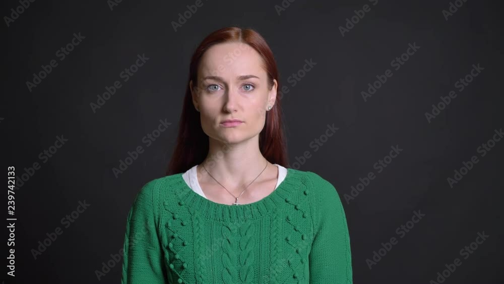 Closeup of beautiful caucasian female with red hair looking straight at camera with neutral facial expression