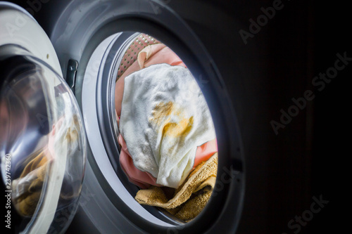 women's hands are holding dirty things in the washing machine
