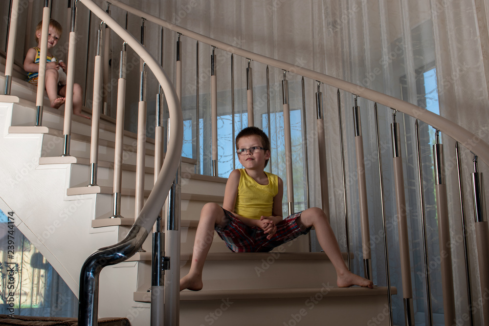 Cute blonde boys play on stairs inside house. Children are happy together on vacation. Cute blonde boys play on stairs inside house. Children are happy together on vacation.