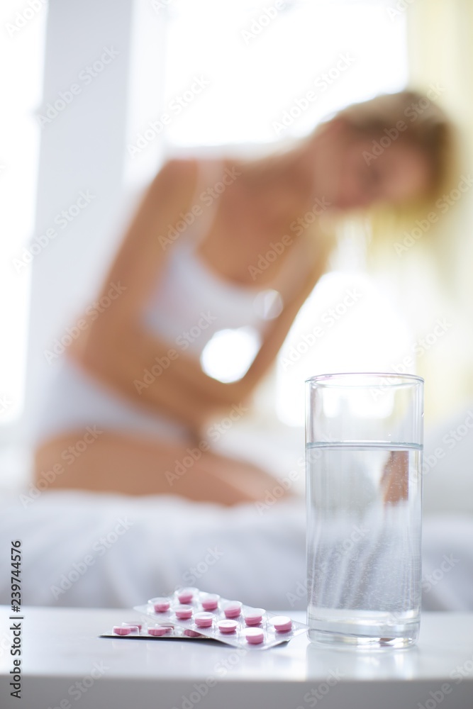 Young beautiful woman with pills lying on bed in bedroom Young beautiful woman with pills lying on bed in bedroom
