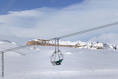 Snowy slope with new-fallen snow, ski-lift and blue sky with clouds photo