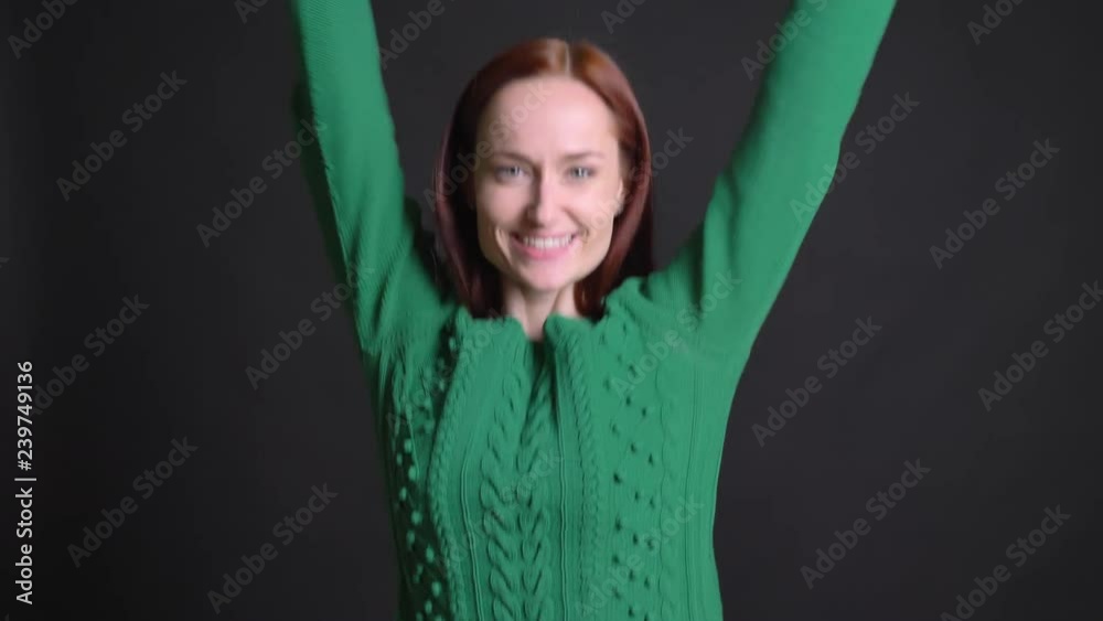 Closeup portrait of attractive caucasian female with red hair dancing happily and perfoming disco moves Closeup portrait of attractive caucasian female with red hair dancing happily and perfoming disco moves