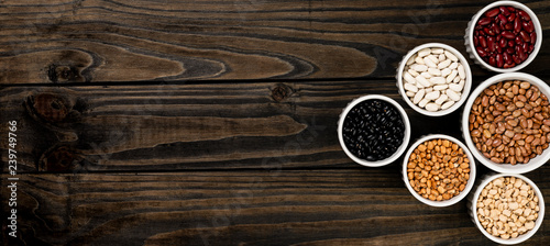 Assortment of beans in a pot. Wooden black background.