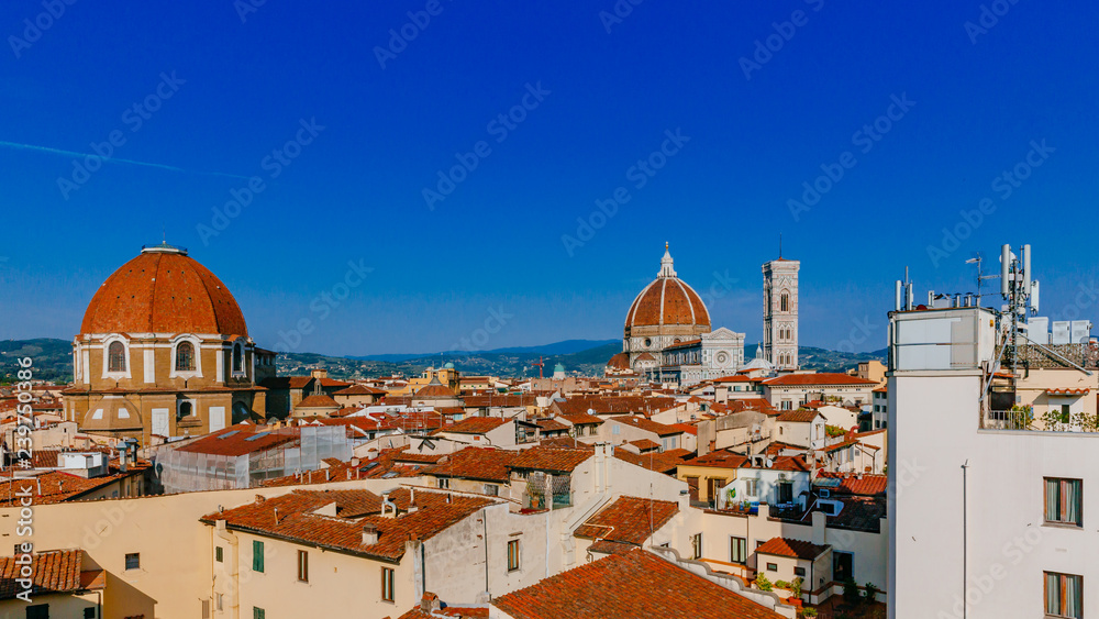 Florence Cathedral, Giotto's Bell Tower, and San Lorenzo Basilica under blue sky, over houses of the historical center of Florence, Italy