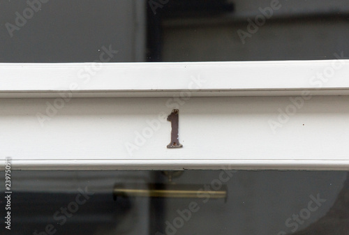 The house number 1 on a white painted door frame in Hertfordshire. photo