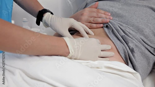 Palpation of the abdomen in the medical center. The doctor examines the patient's stomach, making a clinical examination of the body