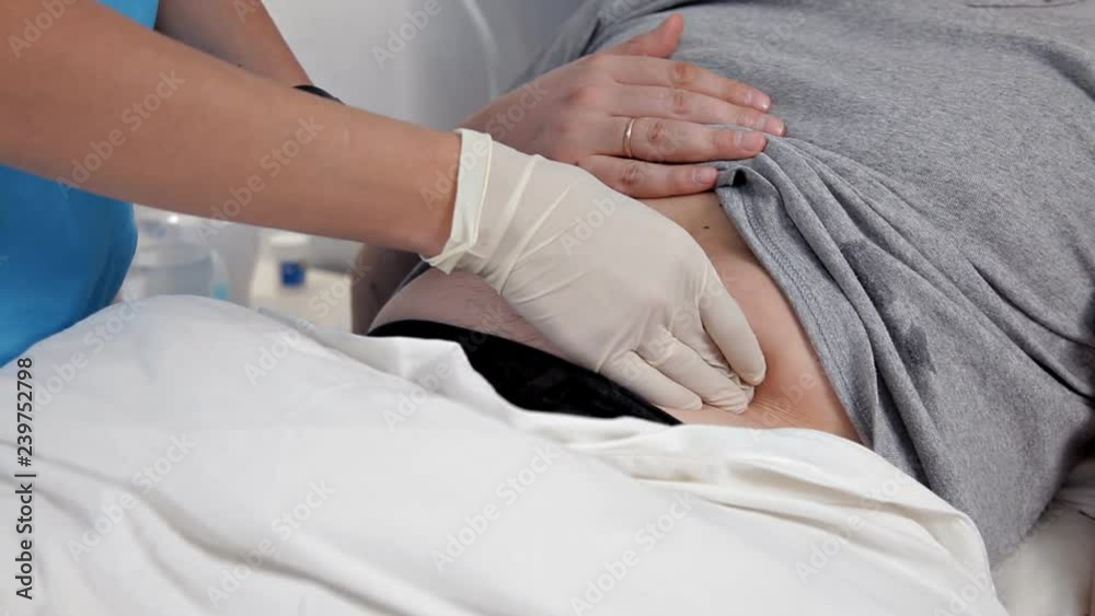Palpation of the abdomen in the medical center. The doctor examines the patient's stomach, making a clinical examination of the body Palpation of the abdomen in the medical center. The doctor examines the patient's stomach, making a clinical examination of the body