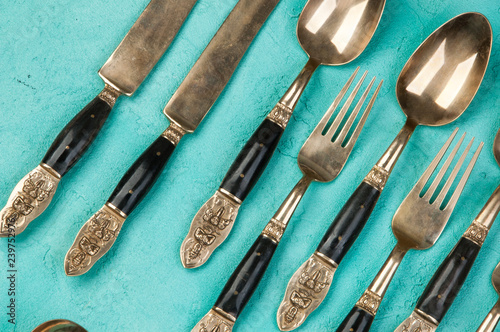 Brass spoons, forks and knives on concrete background.