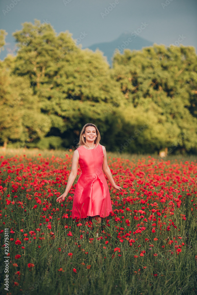 Beautiful woman enjoying nice day in poppy field, wearing pink dress Beautiful woman enjoying nice day in poppy field, wearing pink dress