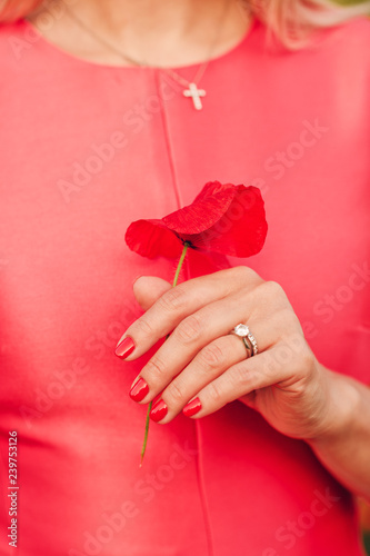 Tableau sur toile Close up image of beautiful woman's hand with perfect red manicure, holding popp
