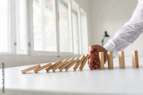 Hand of a business advisor stooping domino effect photo