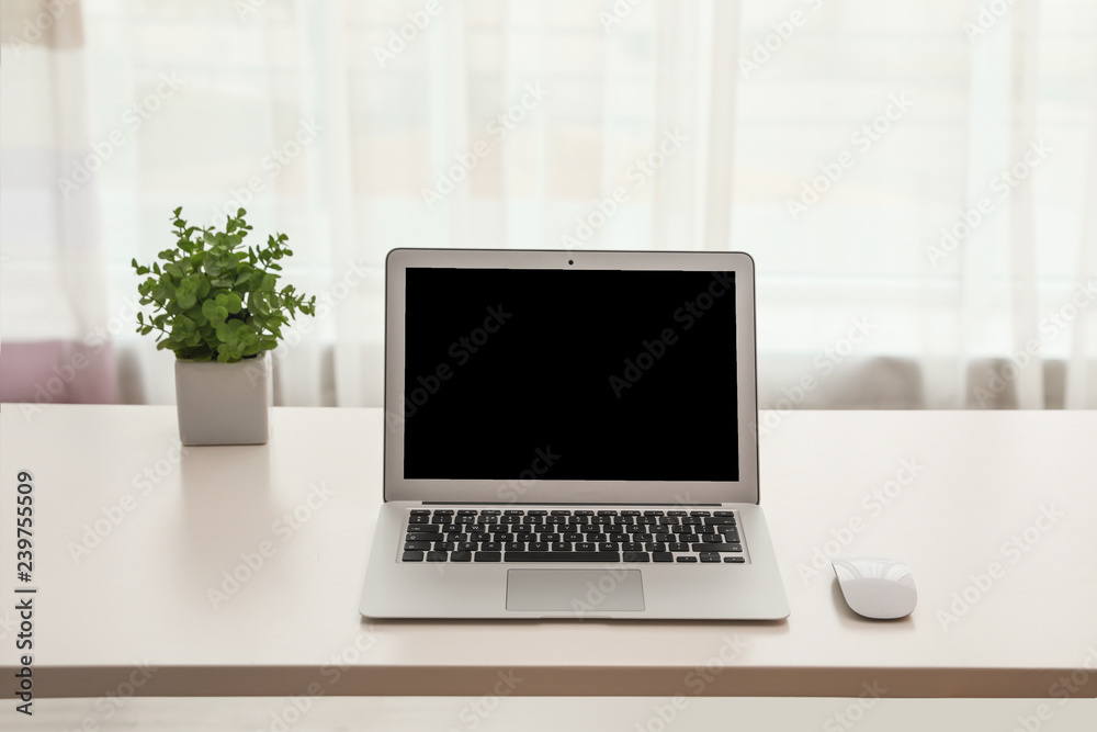 Fototapeta premium Laptop with computer mouse on table indoors. Space for text