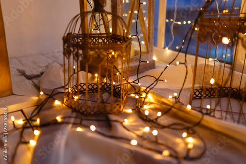 Cages for birds covered with garland with yellow lights. Cozy winter or autumn morning at home. Warm blanket, garland with lights Swedish concept hygge.