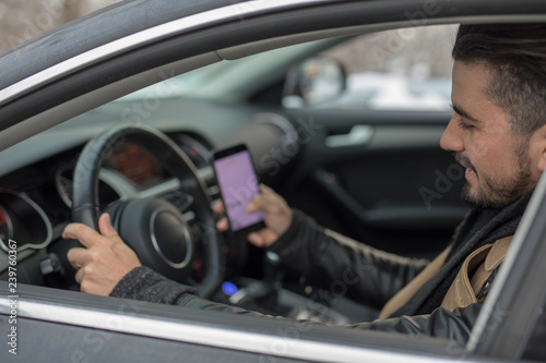 Handsome young man texting and driving at the same time