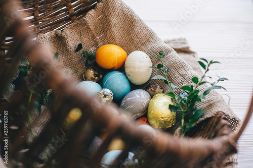 Tableau sur toile Stylish easter eggs on cloth in rustic basket on white wooden background