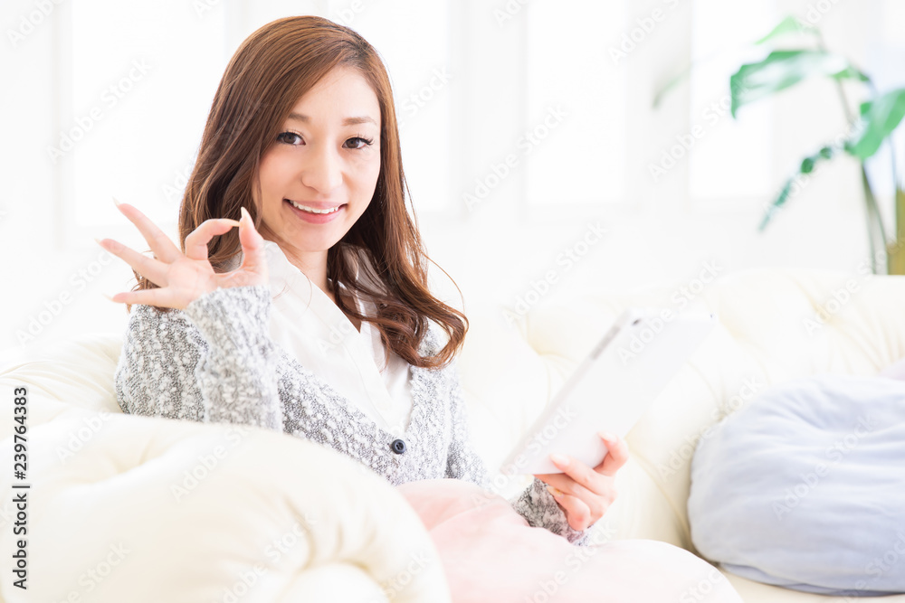 部屋でタブレットを見る女性 部屋でタブレットを見る女性
