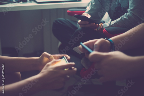 Close up of three pair of hands of young millennial teenager addicted to technology playing with smartphones together in on line life and activity - messaging and chatting on social networks apps