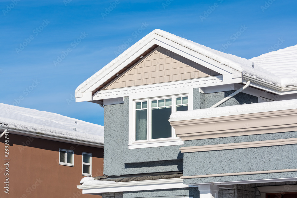 A perfect neighborhood. Top of new luxury residential house in snow. North American family house on winter sunny day A perfect neighborhood. Top of new luxury residential house in snow. North American family house on winter sunny day