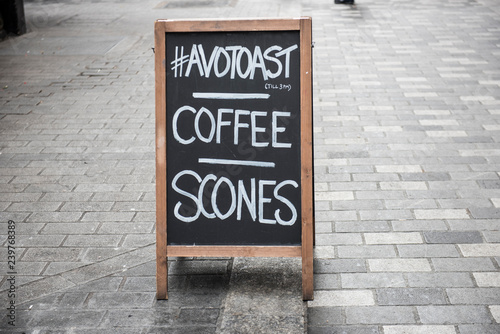 Closeup of the menu of a local coffee shop wriiten on a blackboard. The board is seen kept at the side of the road. The menu is clearly visible along with the concrete road.