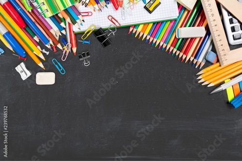 Colorful school supplies on blackboard background