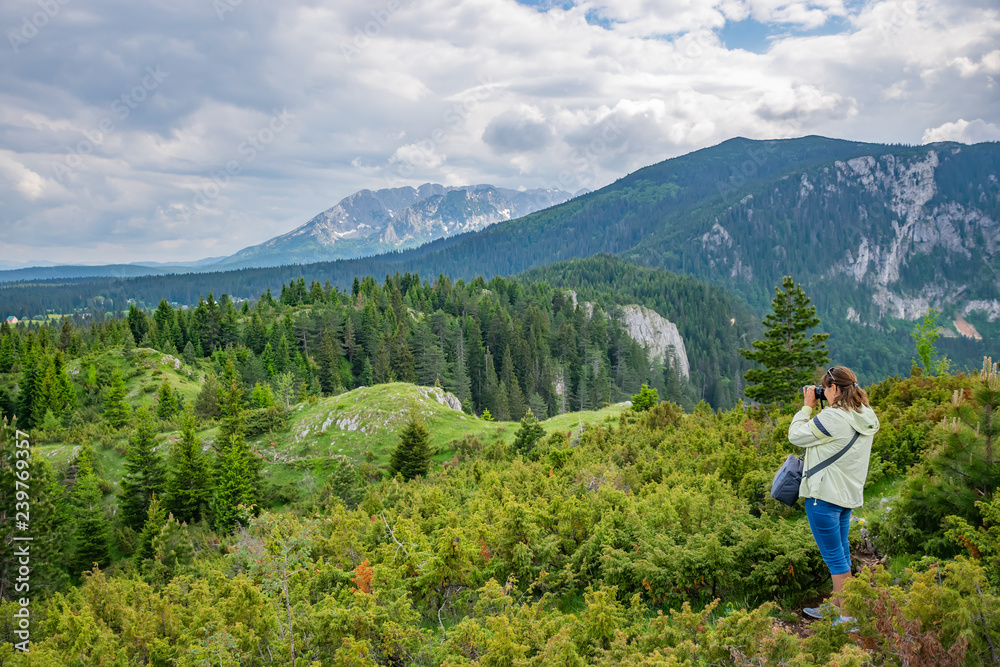 A girl photographer makes a snapshot of a magnificent mountain landscape.