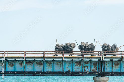 Stacks of barbed wire, wired fence metal, steel rolls on dollies on old seven mile bridge, water, ocean, sea at overseas highway road in Florida keys