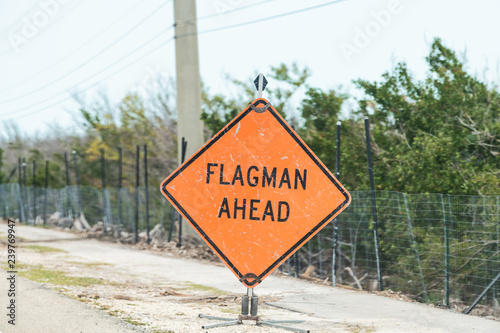 Flagman ahead traffic road sign in red, orange color, signal for drivers on overseas highway road, US1 about utility, construction, repair work, workers