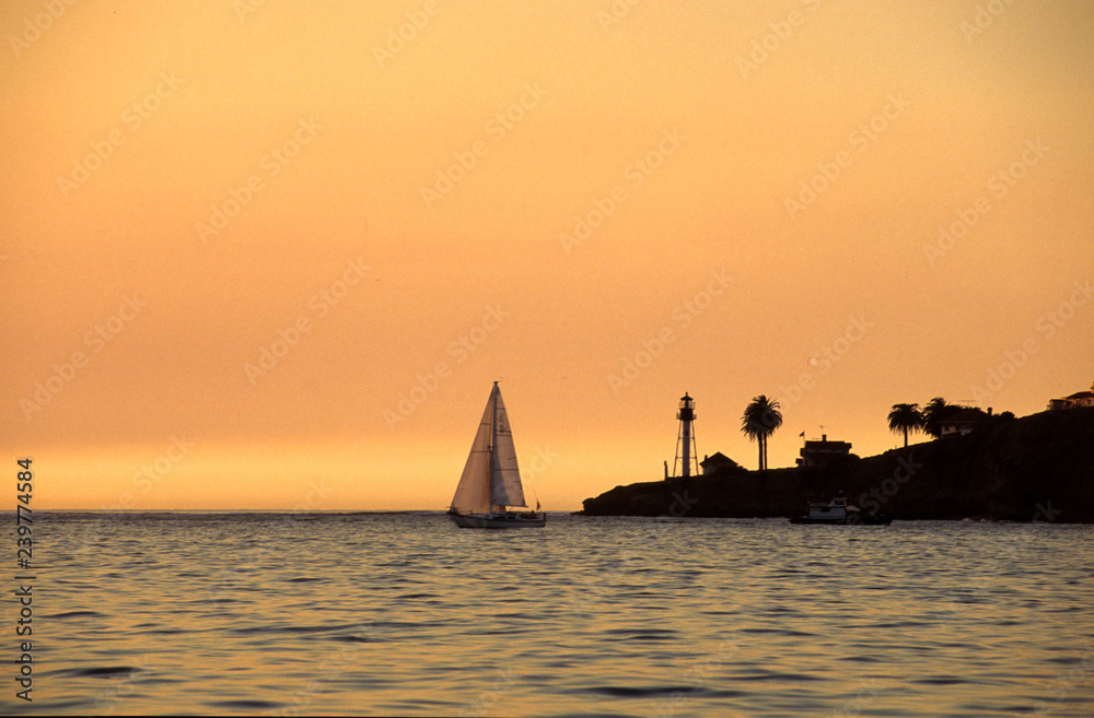sunset at the sea with sailboat and lighthouse