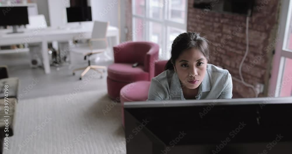 Young adult female standing and working on a desktop computer Young adult female standing and working on a desktop computer