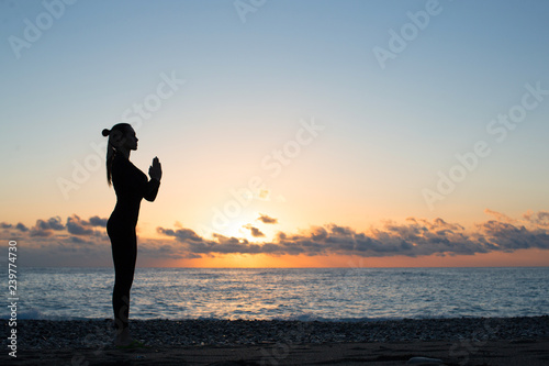 silhouette of woman doing greeting to the sun on the beach at sunrise  morning yoga
