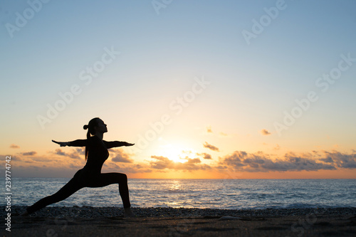 silhouette of woman doing yoga on the beach at sunrise