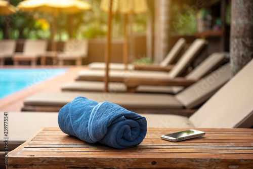 Holiday week end , relax concept,towel and smarthphone on wooden table near  bench pool villa beach side - Image