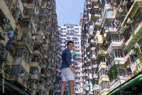Asia Man standing in front of Famous building name Yick Fat Yick residentrial building at Cheong Fok Cheong in Quarry Bay, Hong Kong with urban housing apartment background. photo
