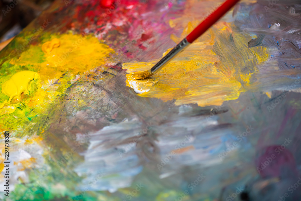 Obraz premium Paint brush on a paint palette with multicolor oil paint